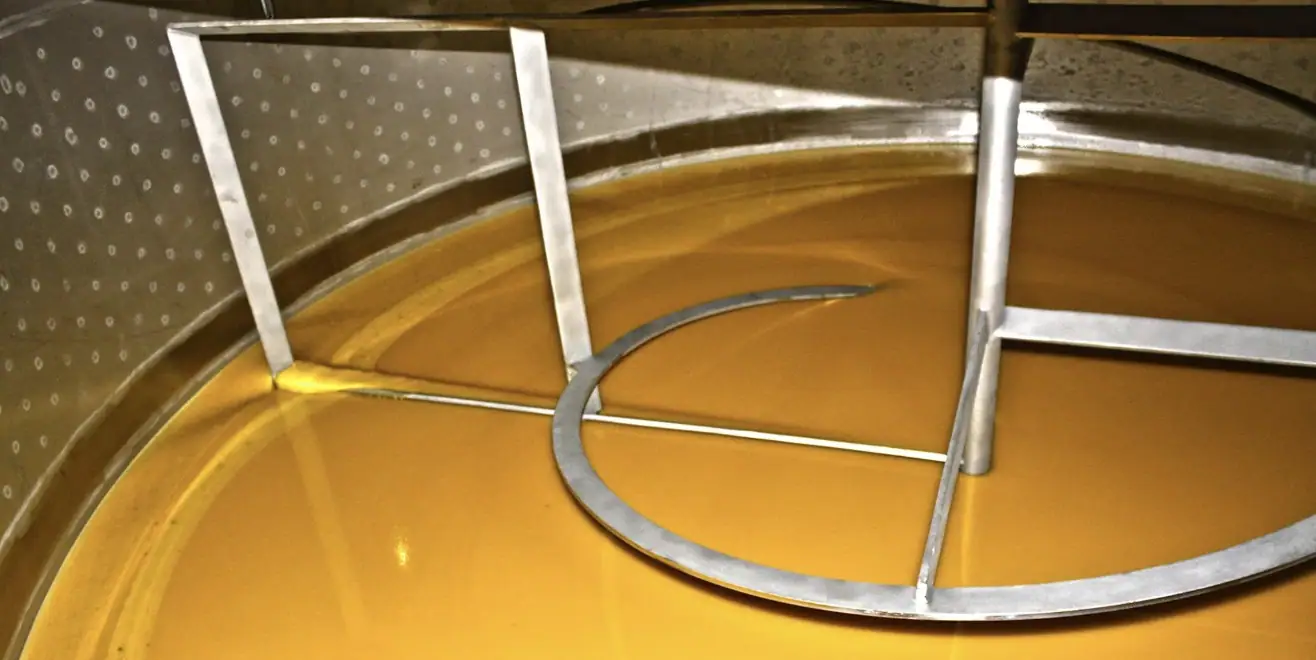 Liquid honey inside the homogenising tank, with the stainless-steel stirrer.